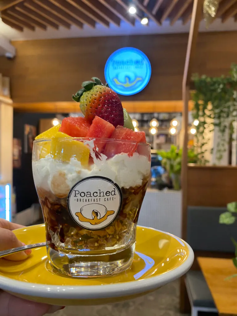 Our Prana Chai Breakfast Parfait in a glass. Granola with yoghurt, topped with melon and strawberries at Poached Breakfast Cafe, Chalong, Phuket. A romantic place for one of the best coffee dates in Phuket.
