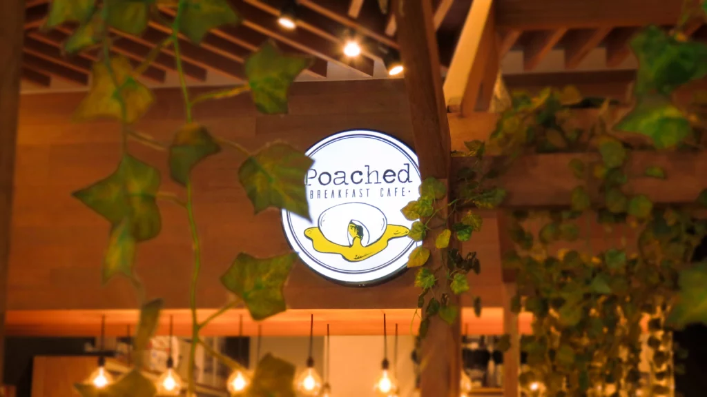 Moody sign and foliage at Poached Breakfast Cafe, a place for the best coffee dates in Phuket.