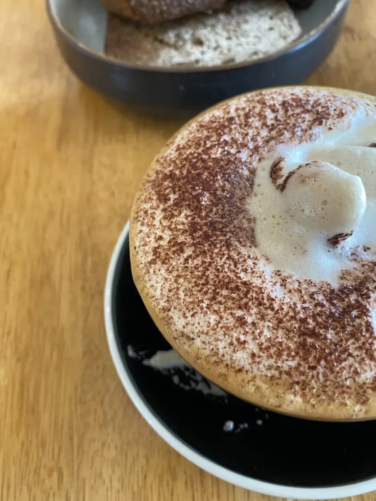 Frothy cappuccino on a table at the number one spot in our Phuket coffee guide: Poached Breakfast Cafe, Chalong, Phuket, Thailand