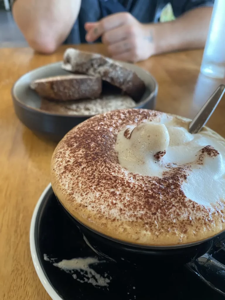 Customer digging into cappuccino foam at the number one spot in our Phuket coffee guide: Poached Breakfast Cafe, Chalong, Phuket, Thailand