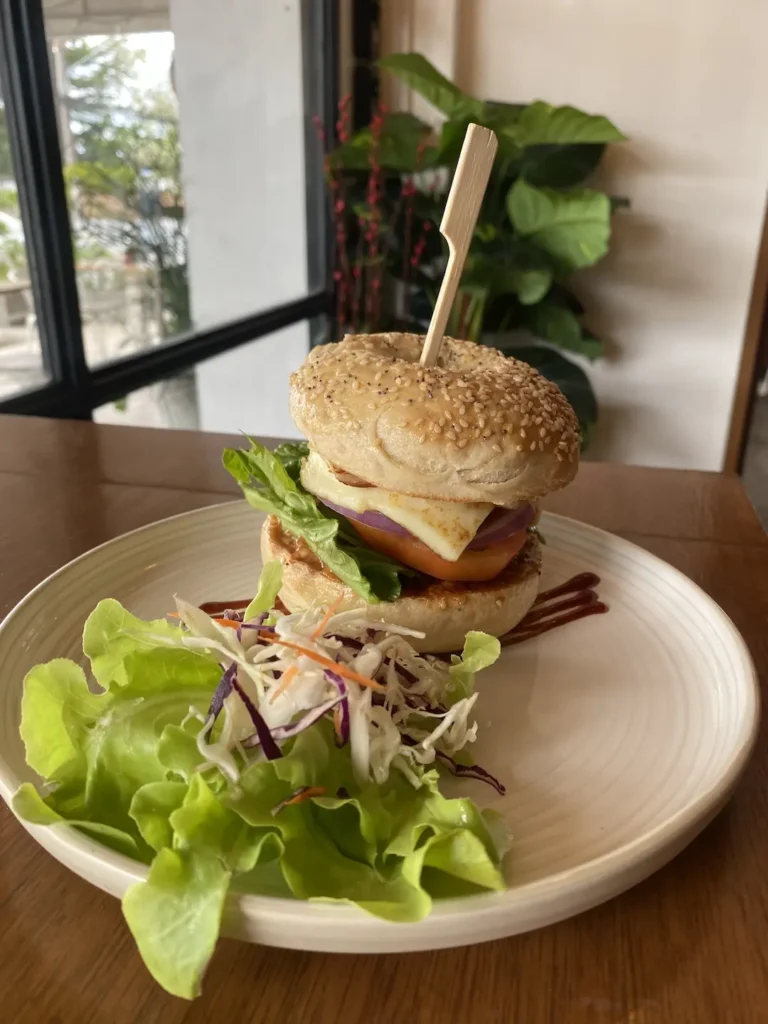 Halloumi Burger with salad on a table by the window. This is the best meal in Chalong and can only be found at Poached Breakfast Cafe, Chalong, Phuket, Thailand