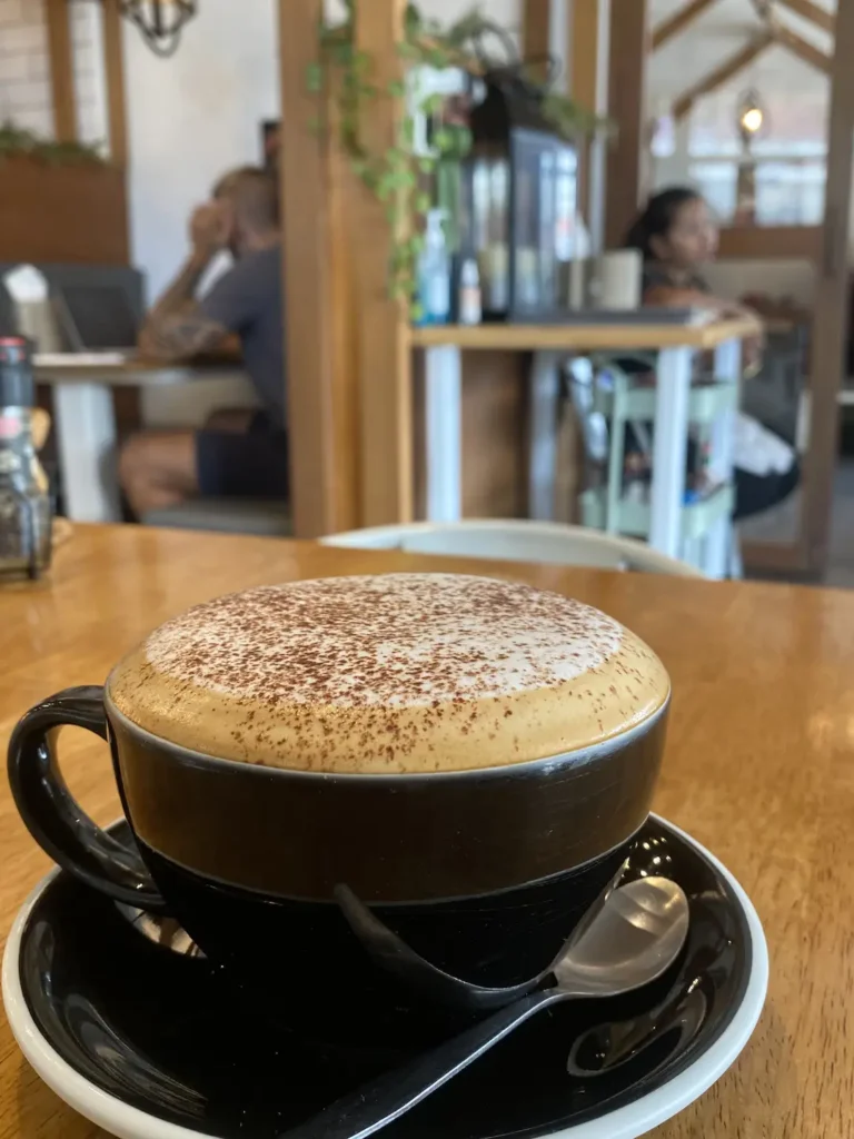 Large Cappuccino with thick foam inside on the table at one of the most famous cafes in Phuket: Poached Breakfast Cafe, Chalong, Phuket, Thailand