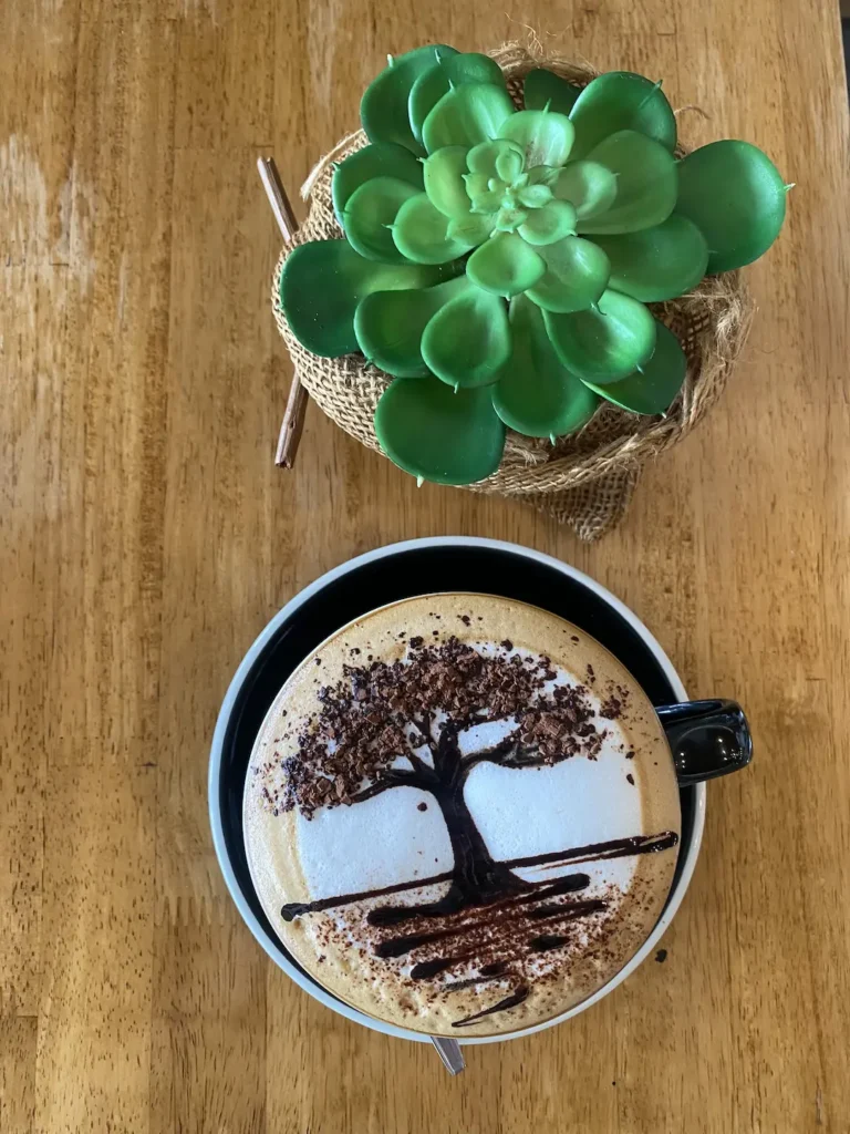Tree latte art on a mocha with a plant next to it at the place with the Best Coffee Art Phuket Has to Offer: Poached Breakfast Cafe, Chalong, Phuket, Thailand