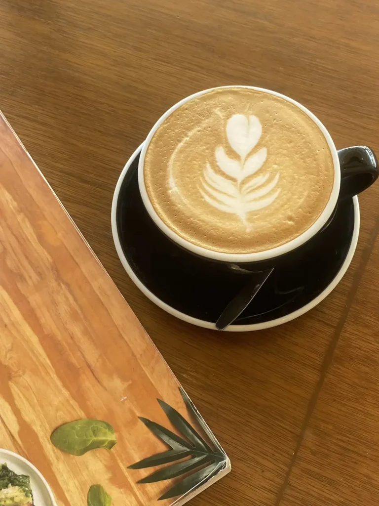 Latte with a flower latte art, next to the cafe menu. The perfect pairing with a breakfast burrito in Chalong at Poached Breakfast Cafe, Chalong, Phuket, Thailand