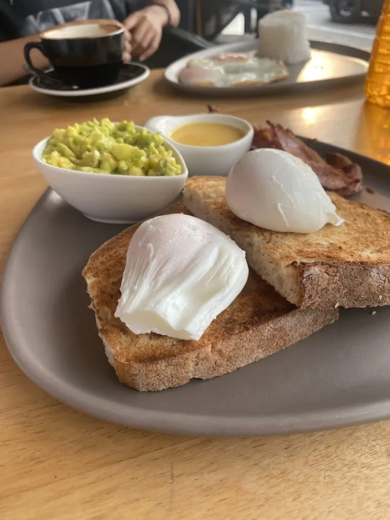Two perfect poached eggs on sourdough bread with smashed avocado and hollandaise sauce. Only at the best spot to see before you head to one of the amazing islands to visit near Phuket: Poached Breakfast Cafe, Chalong, Phuket, Thailand